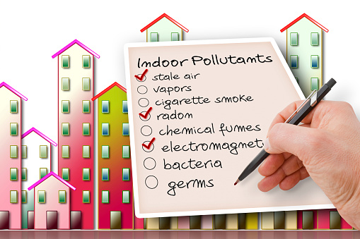 Hand write a check list of indoor air pollutants against a buildings background